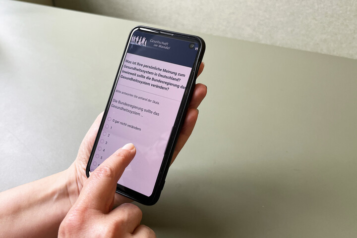 Hände einer Person, die den Fragebogen des German Internet Panels an ihrem Smartphone beantwortet
